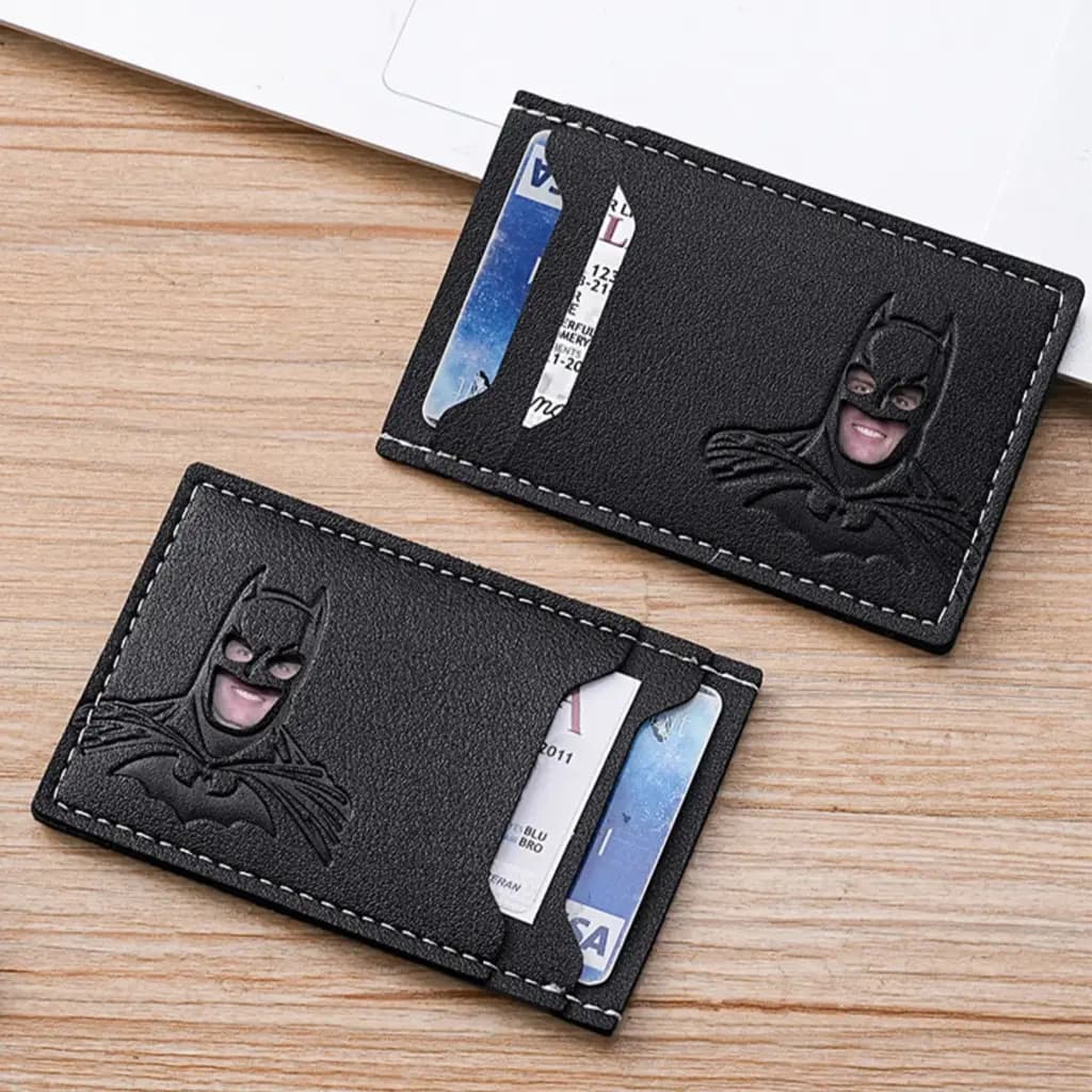 Two slim black PU card holders with cards inside, lying on a wooden desk