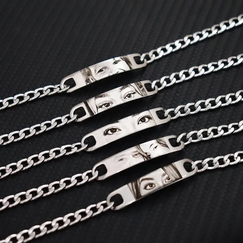 Five silver bracelets with laser-engraved eye plates on a dark background