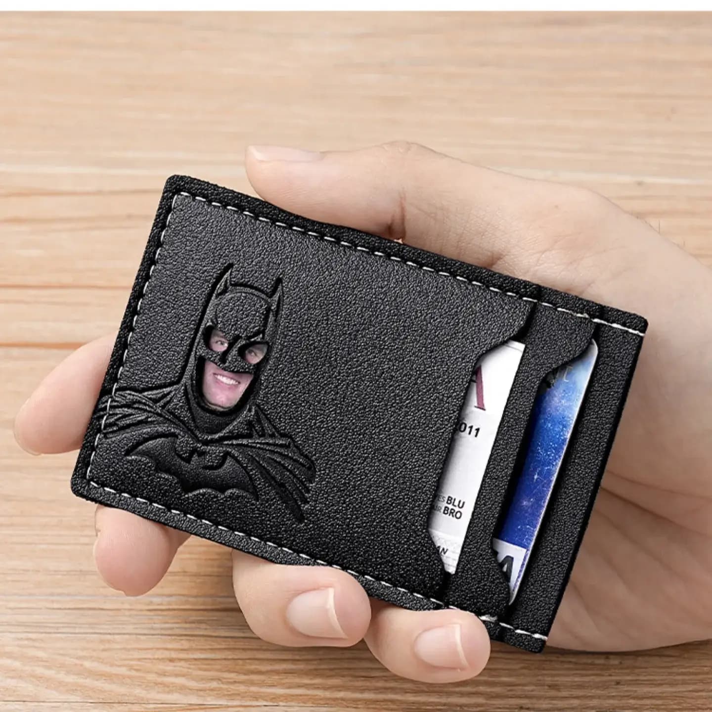 Hands pulling a folded bill from the centre pocket of the card holder